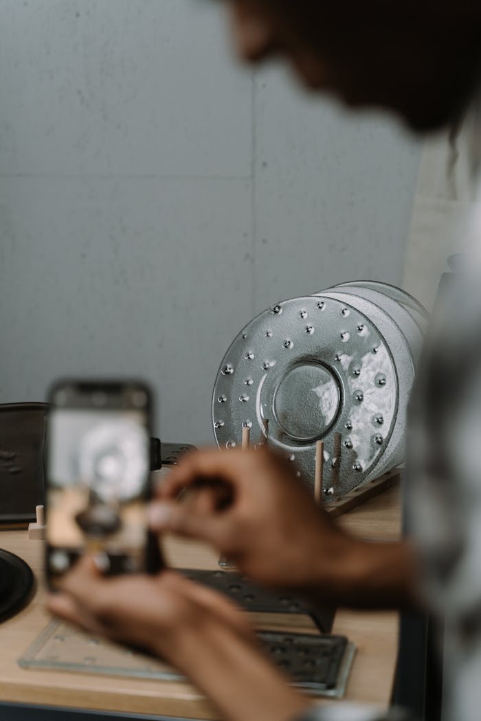 Blurred man with smartphone photographing industrial metal setup.